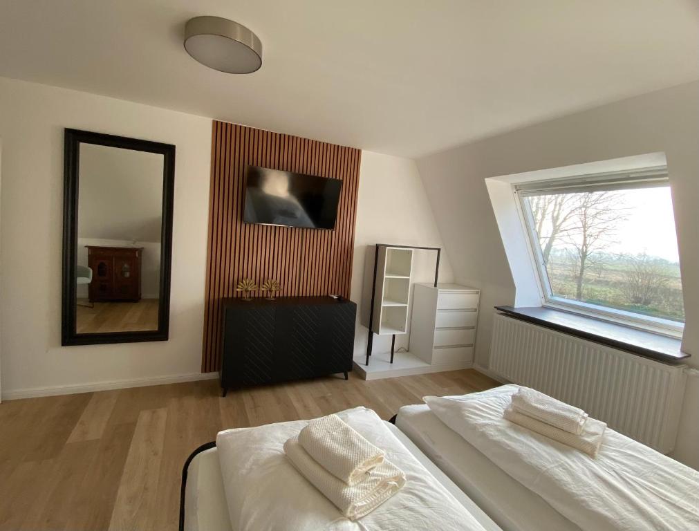 Schlafzimmer mit TV und Holzlamellenwand — Ferienwohnung Weddingstedt